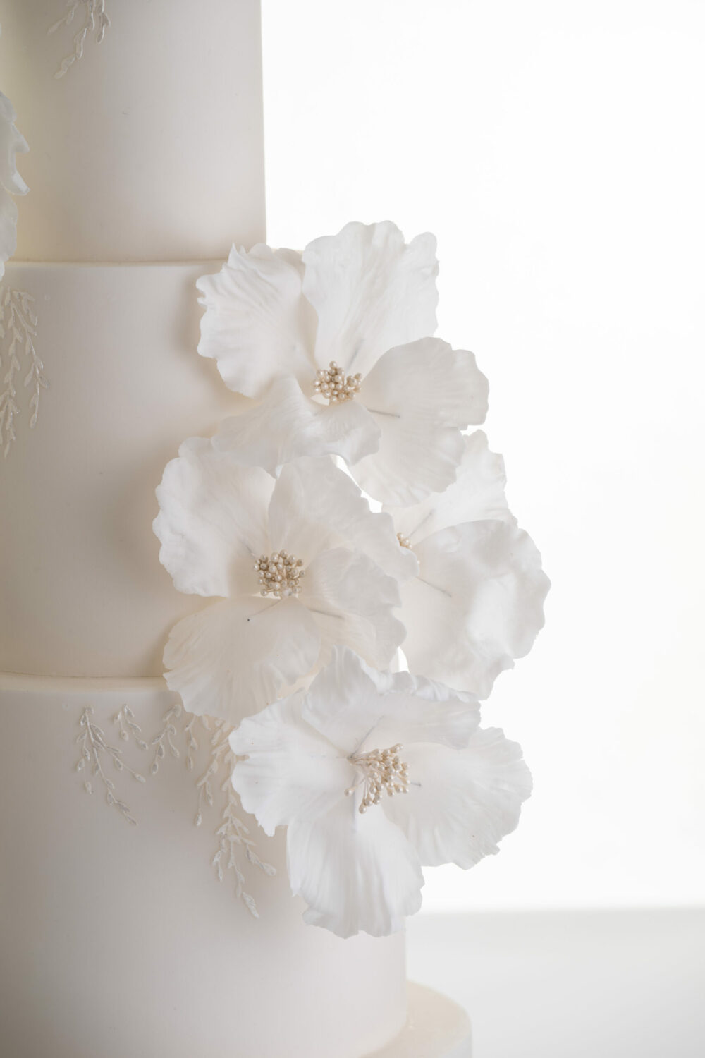 Side detail view of hand-crafted sugar flowers in ivory, on luxury customisable wedding cake, Chic Flowers, by Decorum Taste.