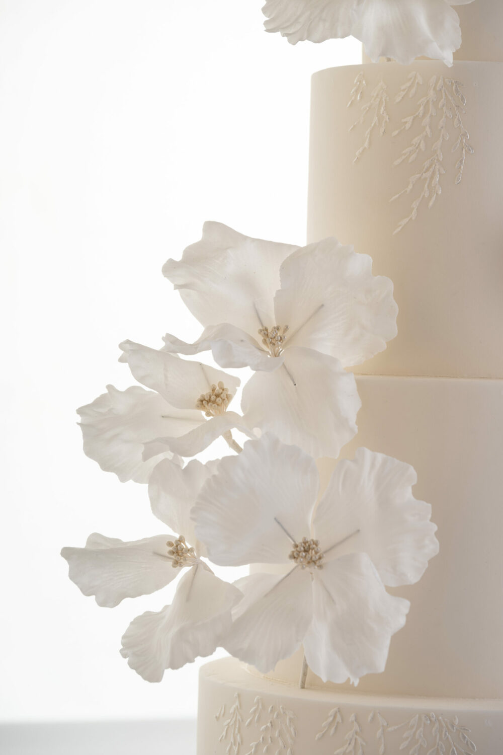 Side detail of hand-crafted sugar flowers on luxury ivory wedding cake, Chic Flowers, by Decorum Taste.