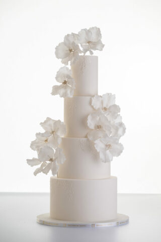 Luxury contemporary 4 tier, customisable wedding cake in ivory with delicate decorative piping and stems of hand-crafted sugar flowers, by Decorum Taste.