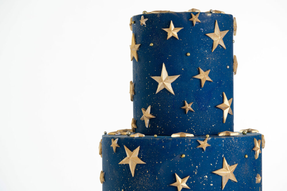 Top tier of luxury contemporary, customisable, celebration cake, Cosmos Star by Decorum Taste, in deep blue with flecks of edible gold and golden stars.