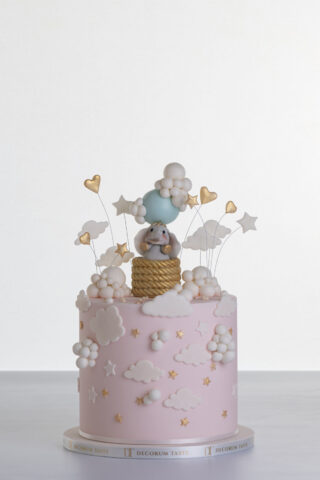 Single tier luxury contemporary, customisable, celebration cake, Cute Elephant by Decorum Taste, in blush pink with hand-crafted elephant in sugar paste sitting on top balancing a balloon, with embellishments of clouds, stars and hearts.