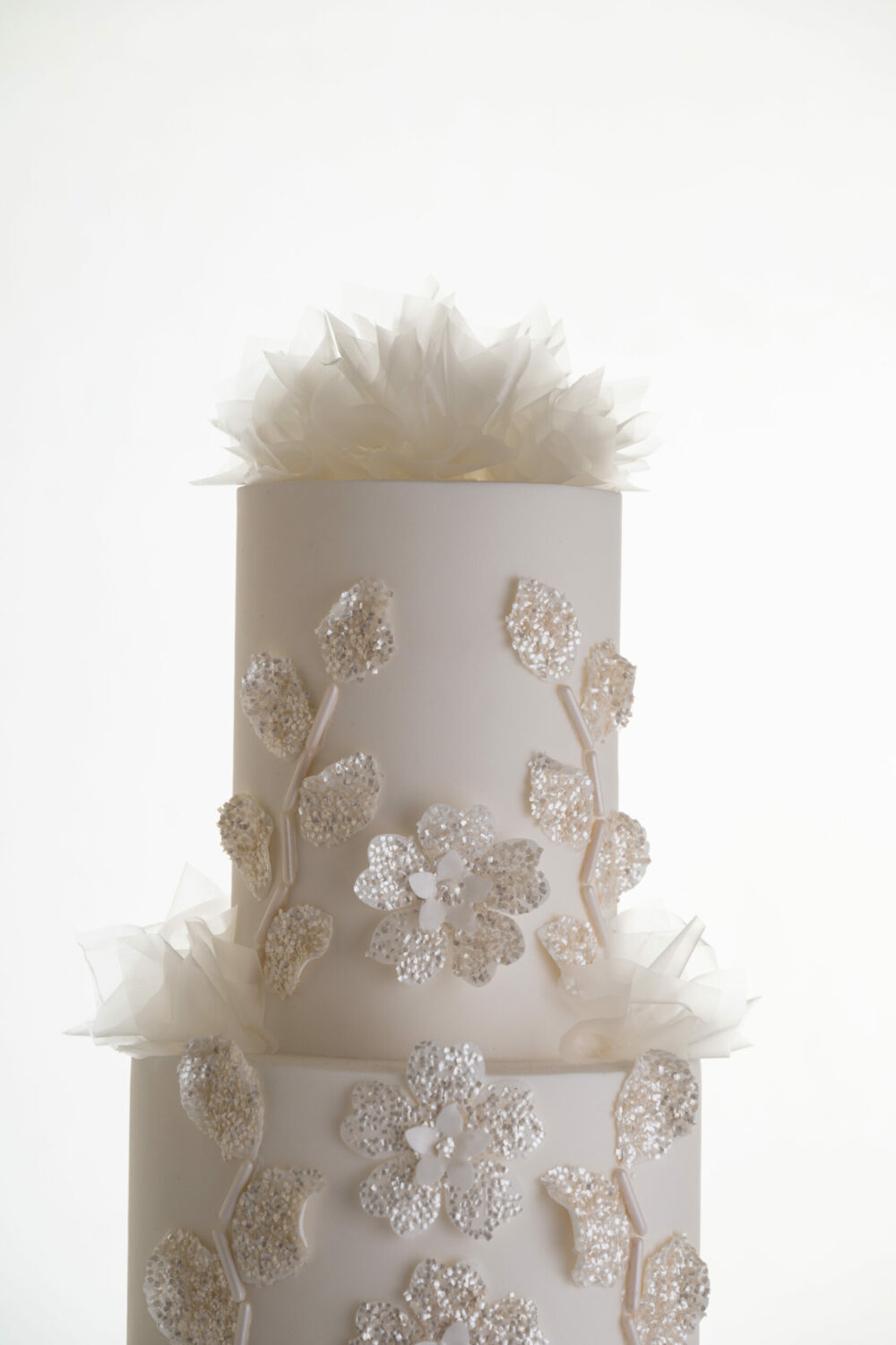 Top 2 tiers of luxury customisable wedding cake, Daphne, by Decorum Taste, with decorative details in edible glitter and delicate rice paper frills.