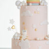 Detail of luxury contemporary, customisable celebration cake, Floating Unicorn by Decorum Taste, decorated in blush pink with embellishments of white clouds, stars with a unicorn at the top sitting in a pastel coloured hot air balloon and another resting on the top of the first tier.