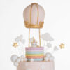 Top tier of luxury contemporary, customisable celebration cake, Floating Unicorn by Decorum Taste, decorated in blush pink with embellishments of white clouds, stars and a unicorn at the top sitting in a pastel coloured hot air balloon.