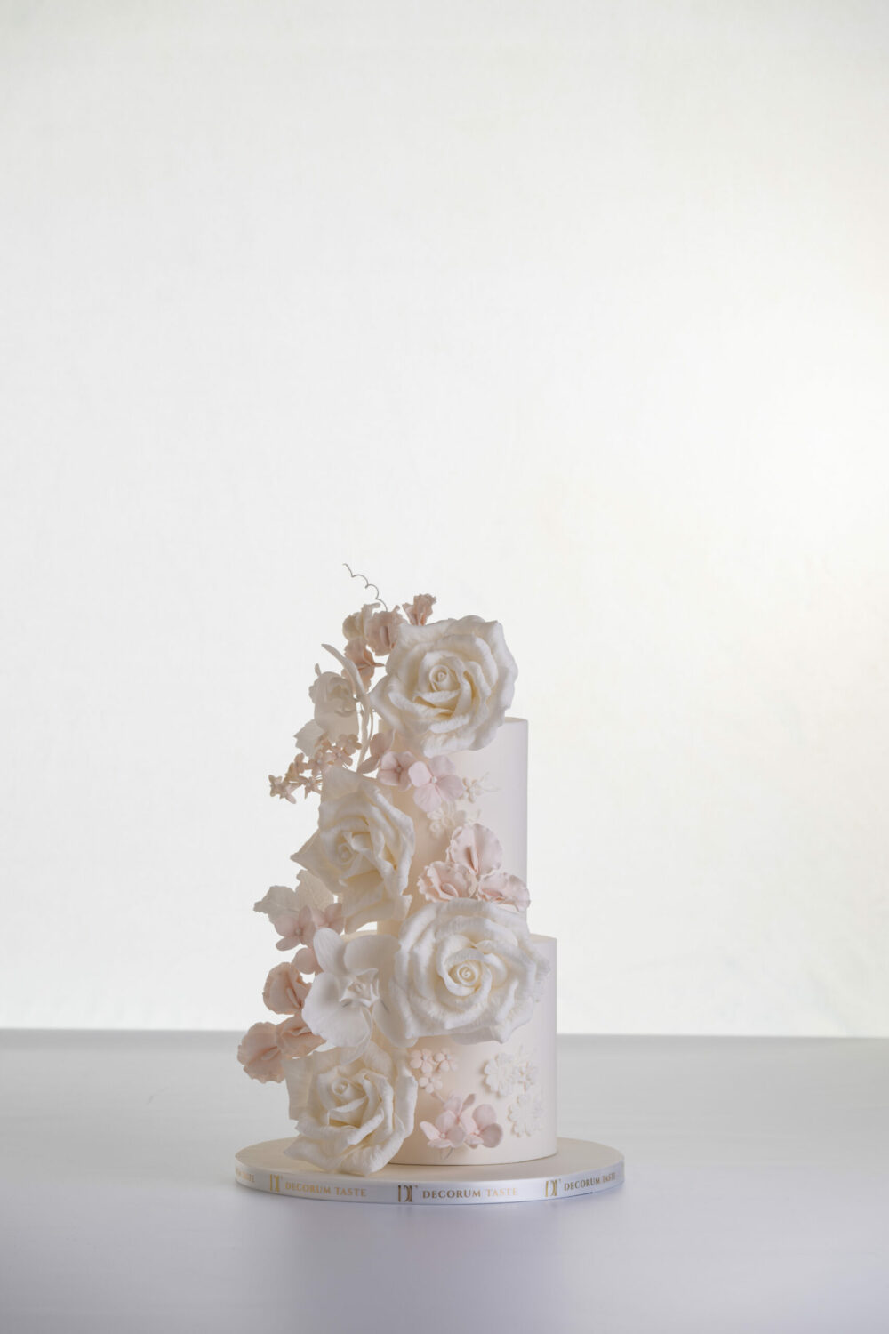 Two tier luxury contemporary, customisable, wedding cake, Floral Cascade by Decorum Taste, decorated with hand-crafted sugar roses, sweet peas and other petals in ivory and blush pink tones.