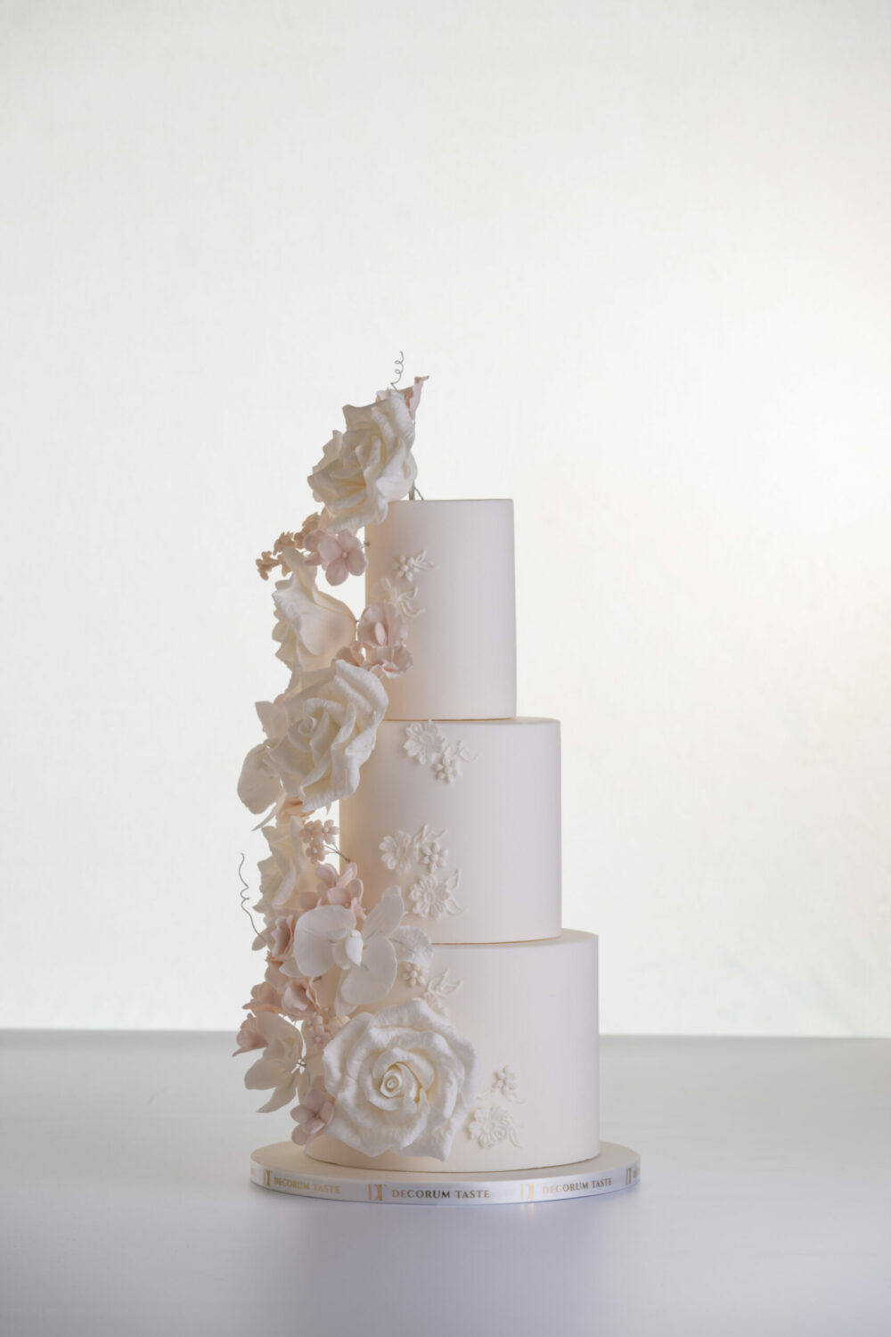 Four tier luxury contemporary, customisable, wedding cake, Floral Cascade by Decorum Taste, decorated with hand-crafted sugar roses, sweet peas and other petals in ivory and blush pink tones.