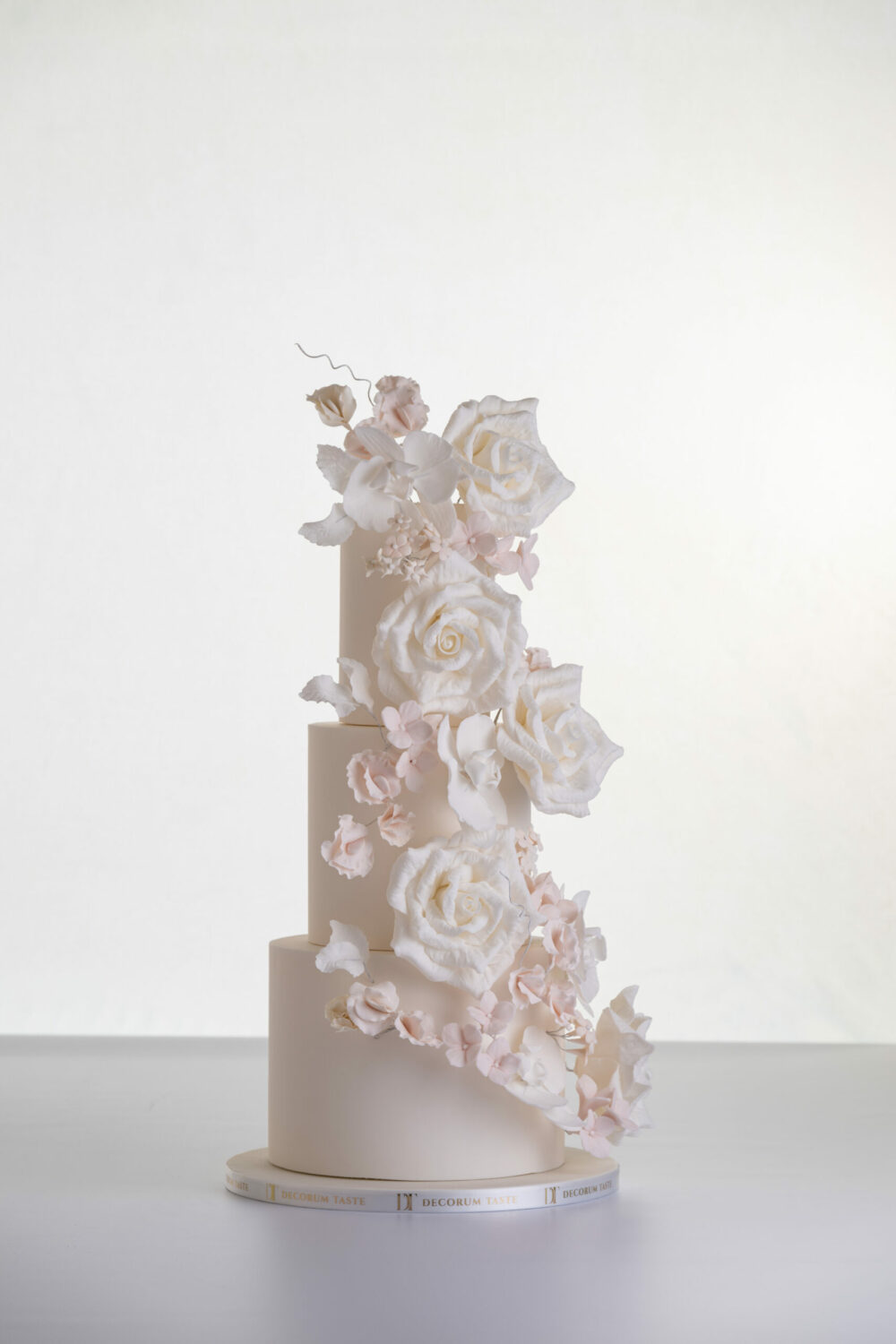 Four tier luxury contemporary, customisable, wedding cake, Floral Cascade by Decorum Taste, decorated with hand-crafted sugar roses, sweet peas and other petals in ivory and blush pink tones.