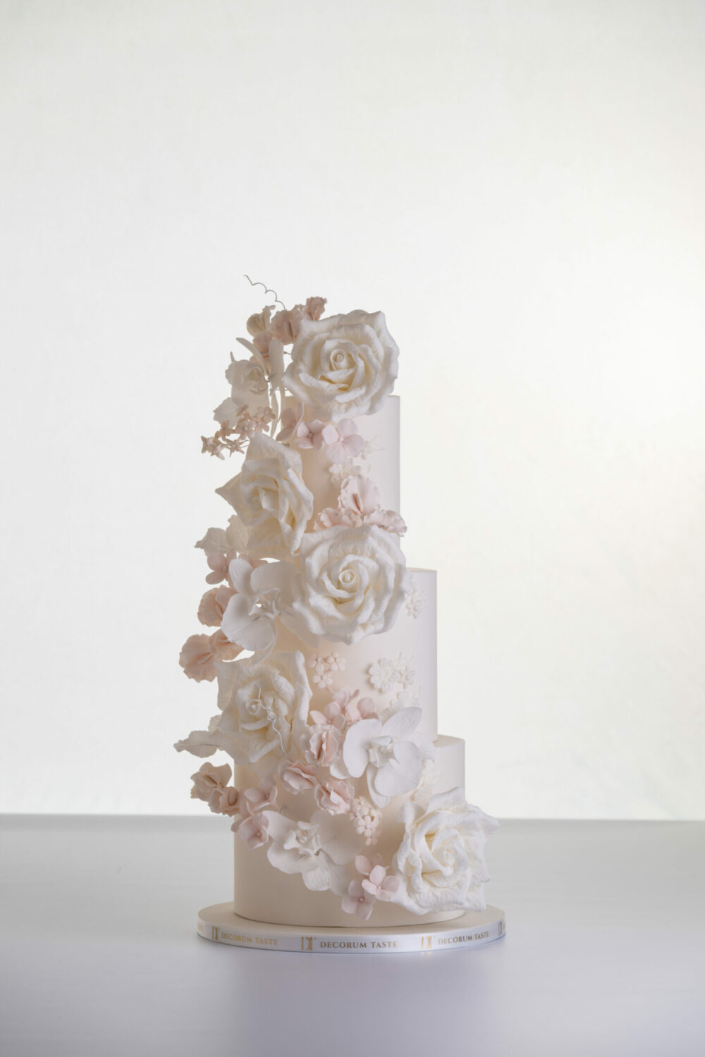 Four tier luxury contemporary, customisable, wedding cake, Floral Cascade by Decorum Taste, decorated with hand-crafted sugar roses, sweet peas and other petals in ivory and blush pink tones.