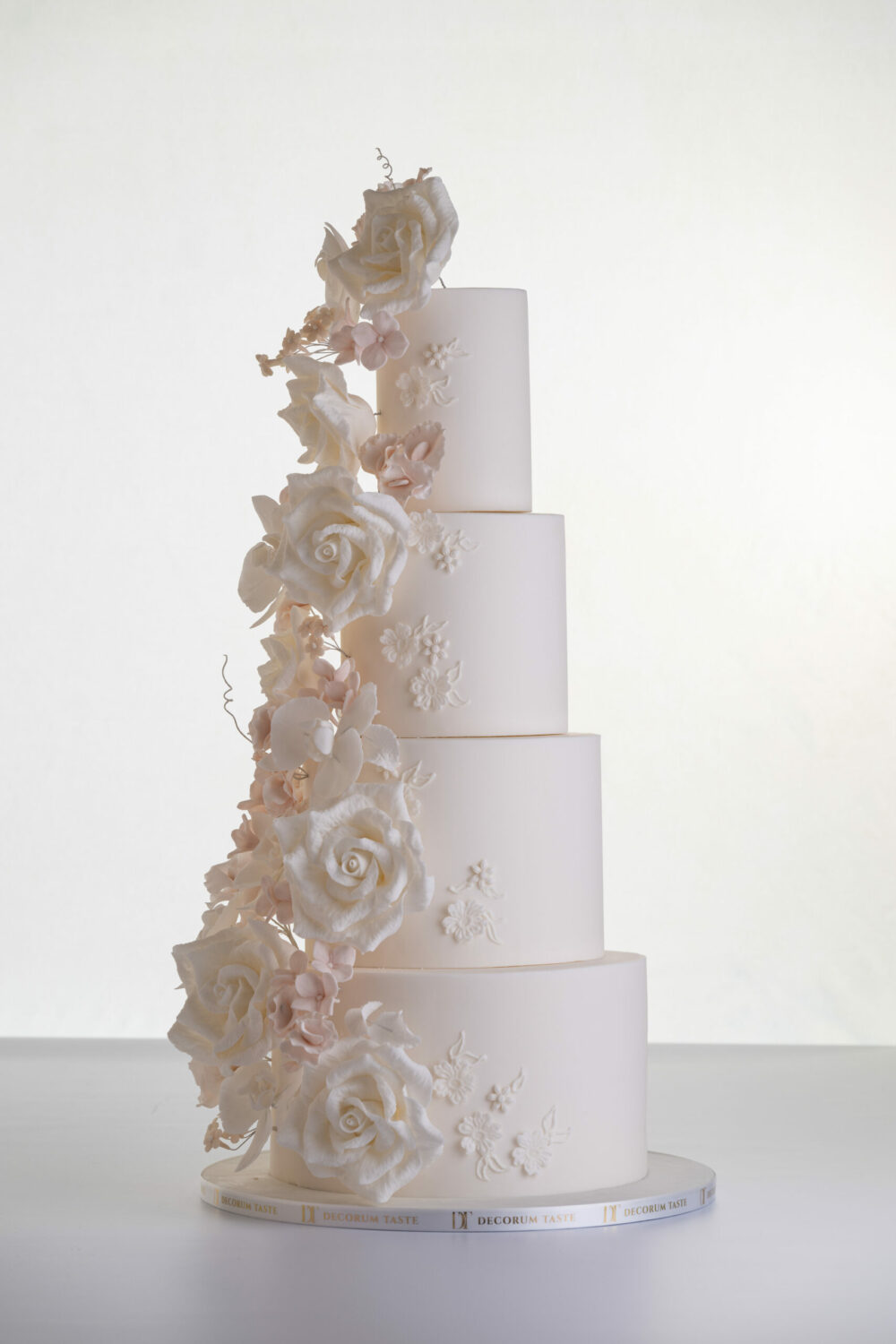 Four tier luxury contemporary, customisable, wedding cake, Floral Cascade by Decorum Taste, decorated with hand-crafted sugar roses, sweet peas and other petals in ivory and blush pink tones.