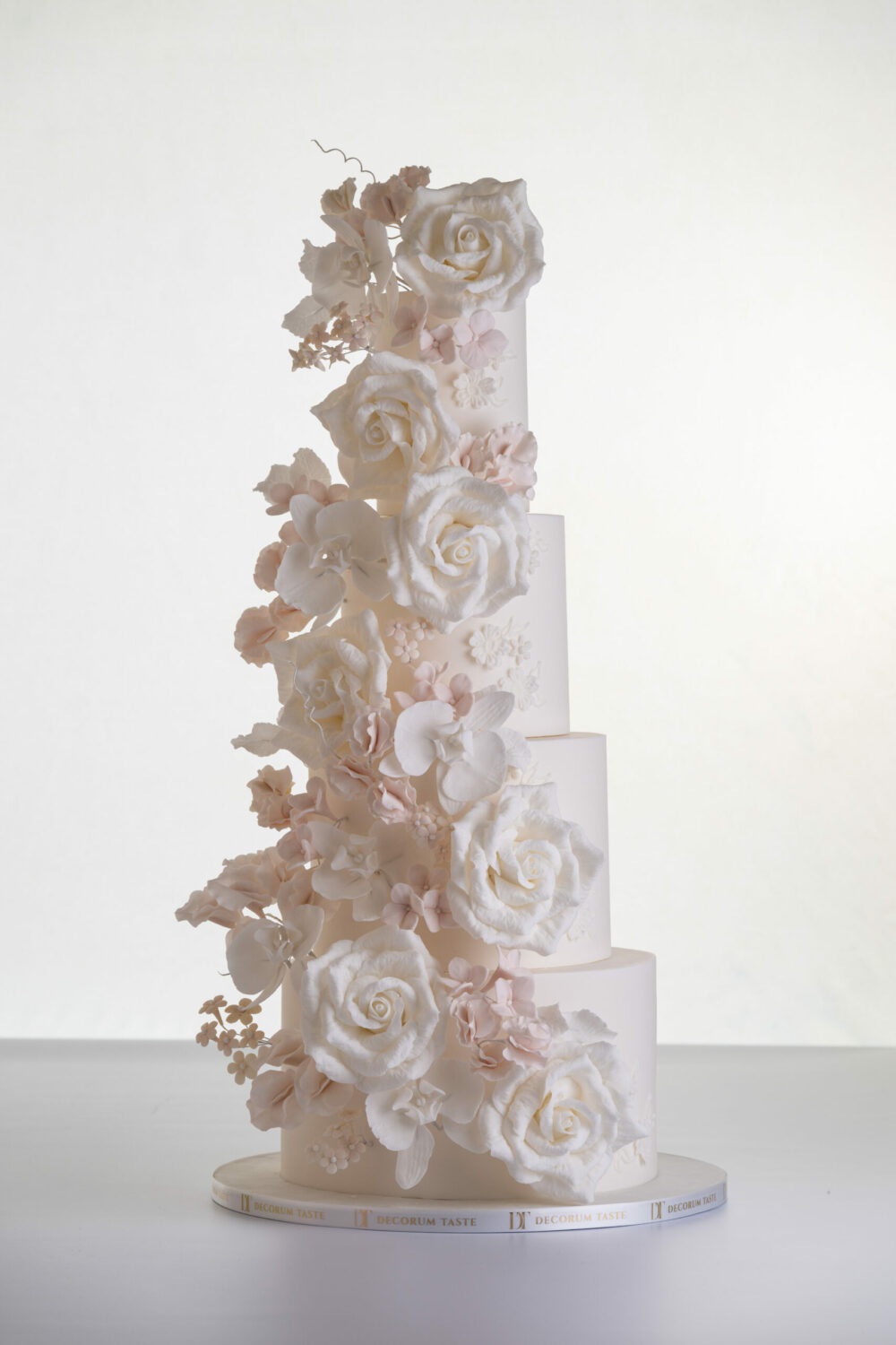 Four tier luxury contemporary, customisable, wedding cake, Floral Cascade by Decorum Taste, decorated with hand-crafted sugar roses, sweet peas and other petals in ivory and blush pink tones.