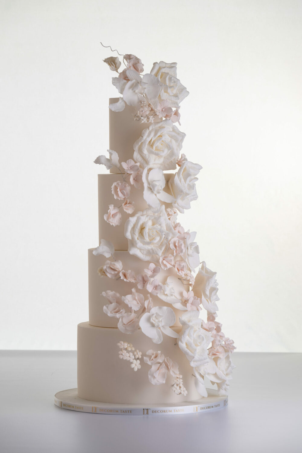 Four tier luxury contemporary, customisable, wedding cake, Floral Cascade by Decorum Taste, decorated with hand-crafted sugar roses, sweet peas and other petals in ivory and blush pink tones.