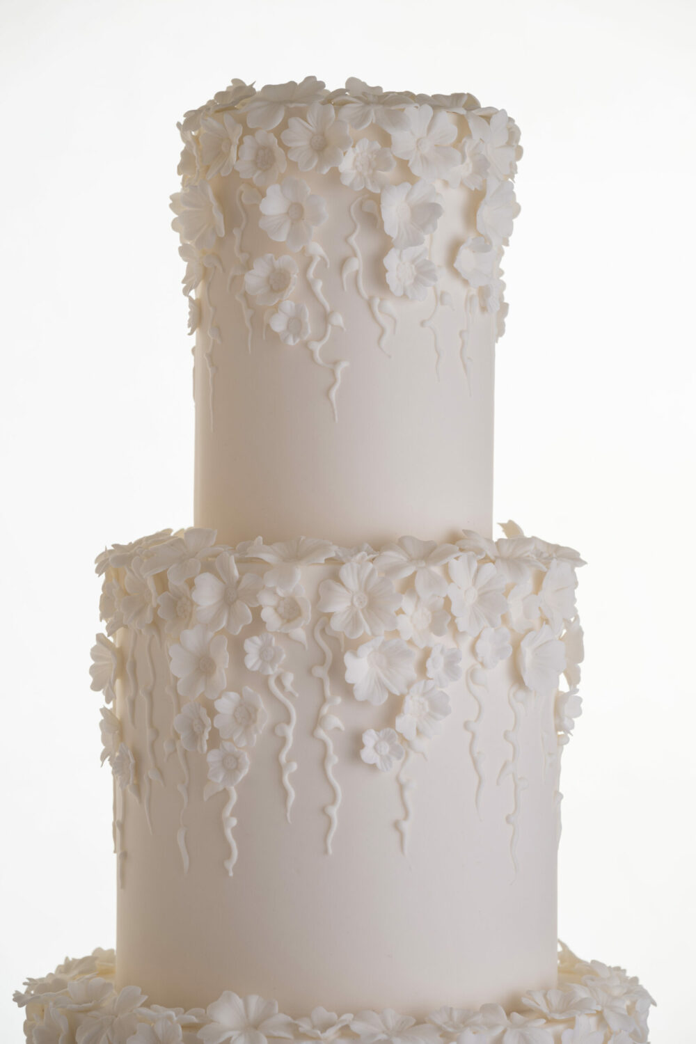 Top two tiers showing the detail of decorative floral embellishments in ivory on luxury contemporary wedding cake, Fountain of Blossom, by Decorum Taste.