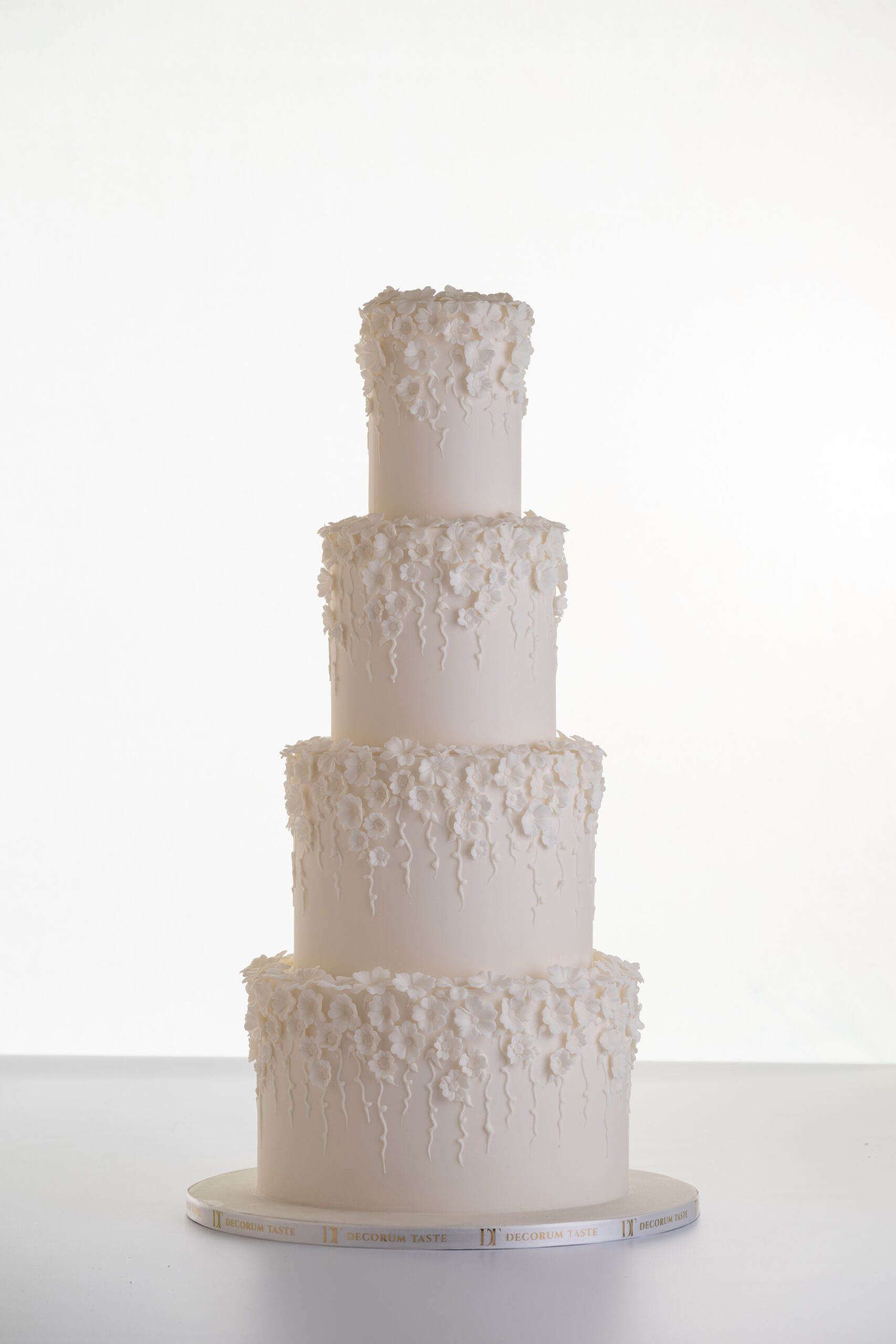 Four tier luxury contemporary, customisable, wedding cake, Fountain of Blossom, by Decorum Taste with cascades of decorative floral embellishments in ivory.