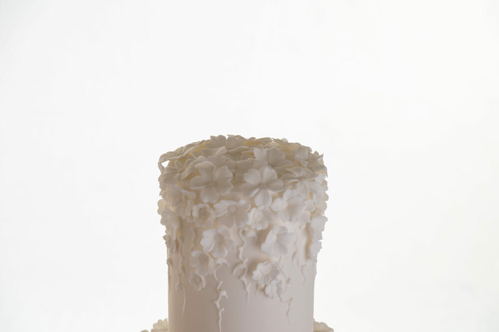 Top tier of luxury customisable wedding cake, Fountain of Blossom, by Decorum Taste showing the decorative floral embellishments in ivory, cascading down the cake.