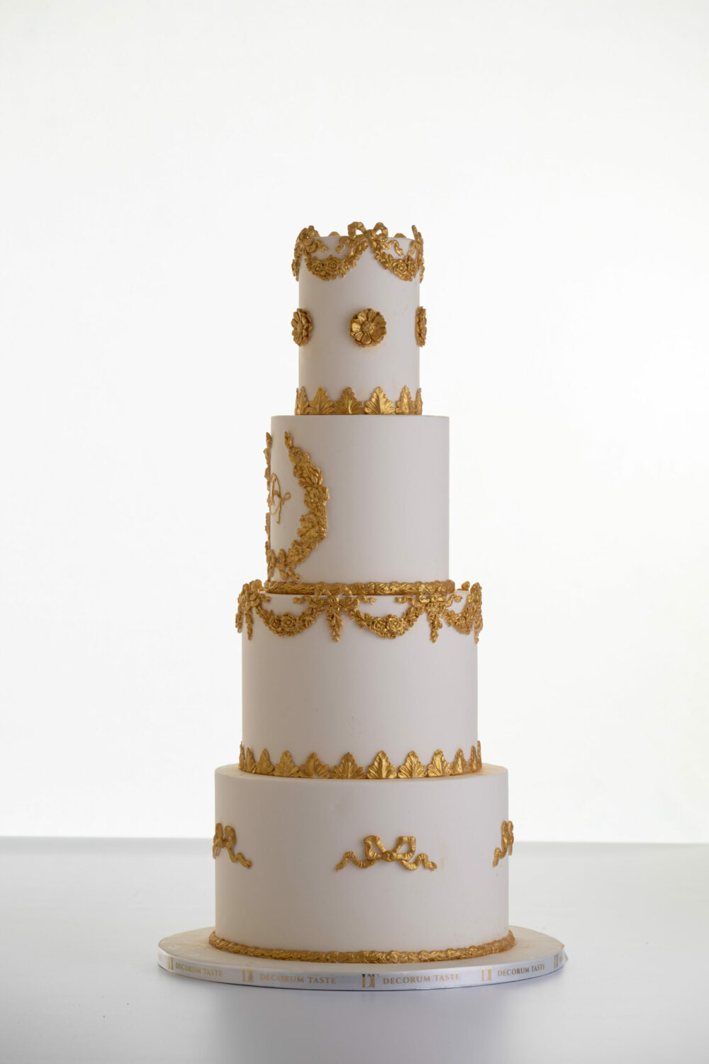 Four tier luxury customisable wedding cake in ivory with gold decorative details by Decorum Taste.