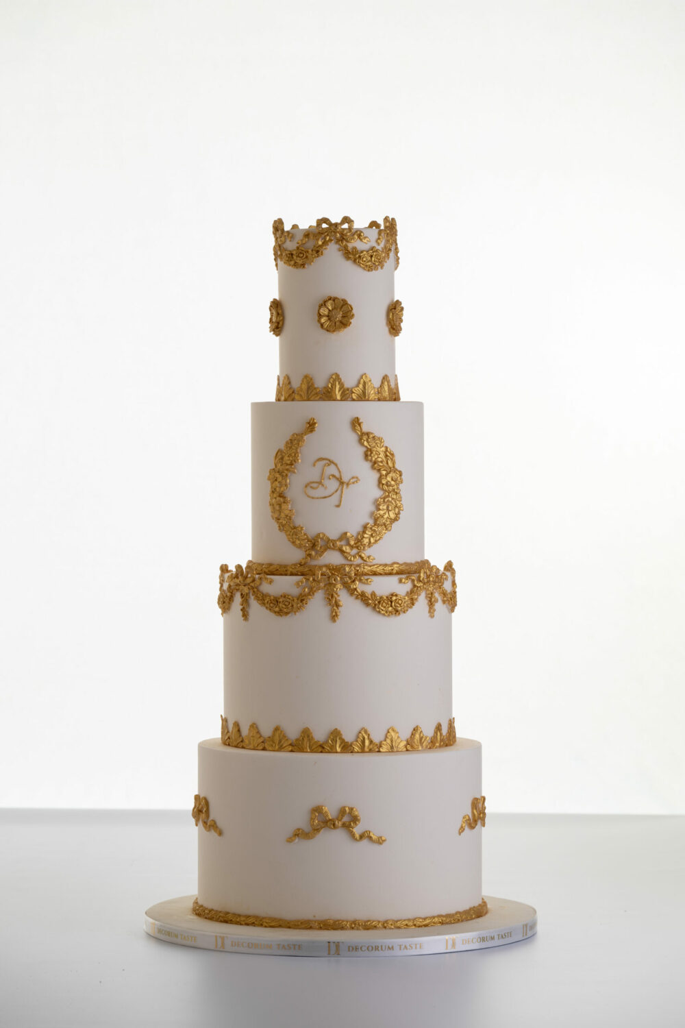 Four tier luxury customisable wedding cake in ivory with gold decorative details by Decorum Taste.