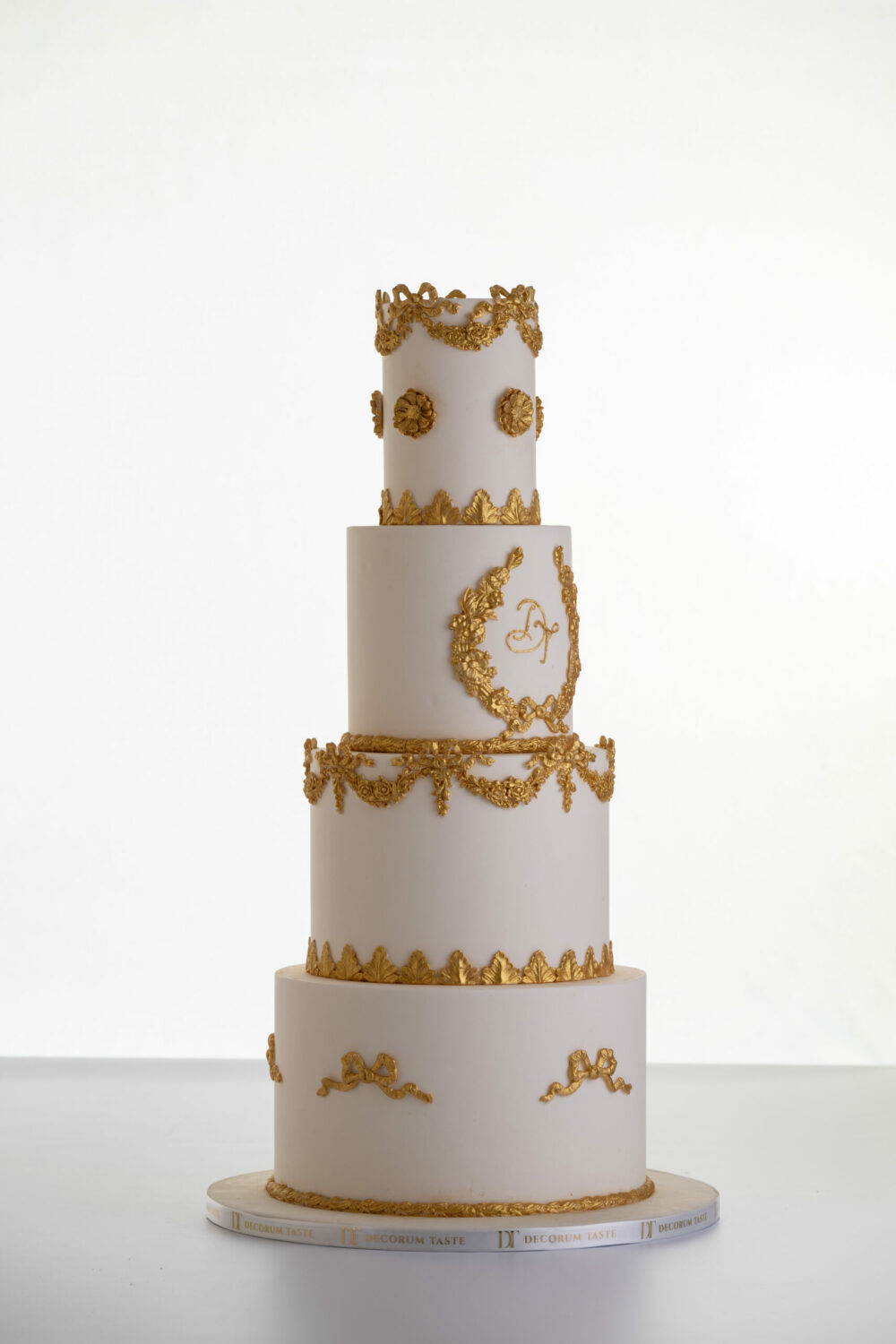 Four tier luxury customisable wedding cake in ivory with gold decorative details by Decorum Taste.