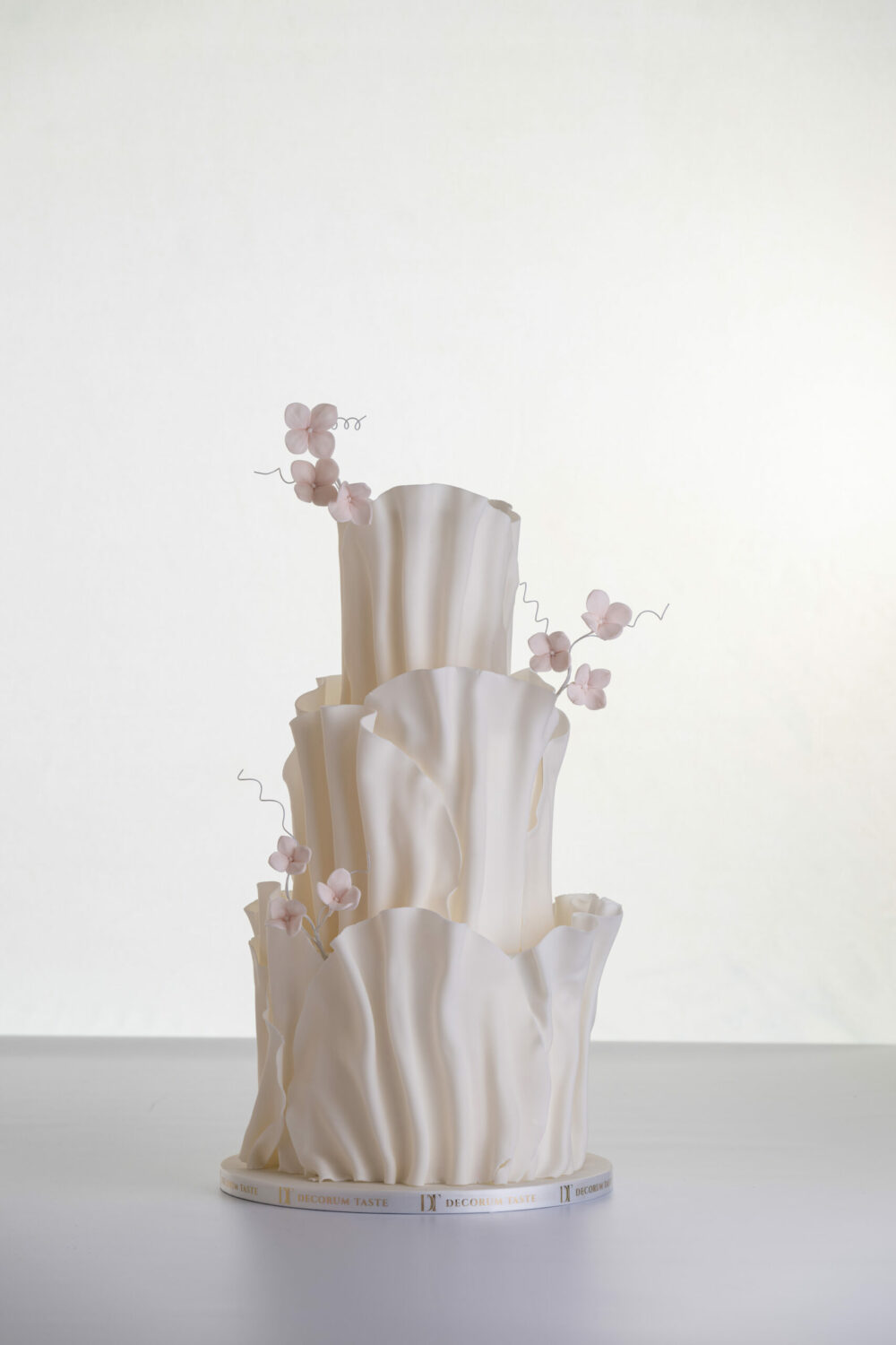 Two tier luxury contemporary, customisable, wedding cake, Modern Ruffles by Decorum Taste, with textured decorative folds and hand-crafted sugar flower stems.