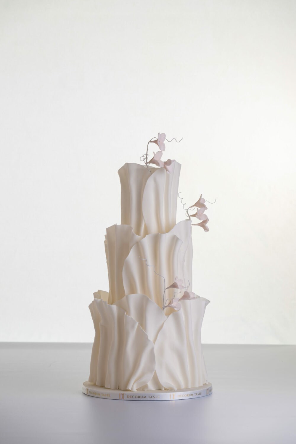 Two tier luxury contemporary, customisable, wedding cake, Modern Ruffles by Decorum Taste, with textured decorative folds and hand-crafted sugar flower stems.