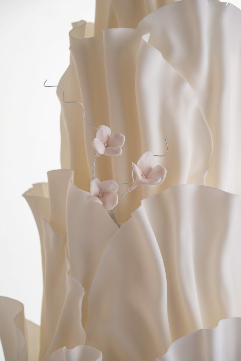 Detail of luxury contemporary, customisable, wedding cake, Modern Ruffles by Decorum Taste, with textured decorative folds and hand-crafted sugar flower stems.