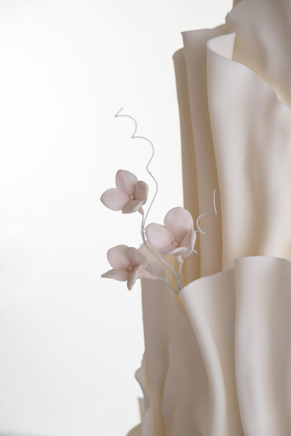 Detail of luxury contemporary, customisable, wedding cake, Modern Ruffles by Decorum Taste, with textured decorative folds and hand-crafted sugar flower stems.