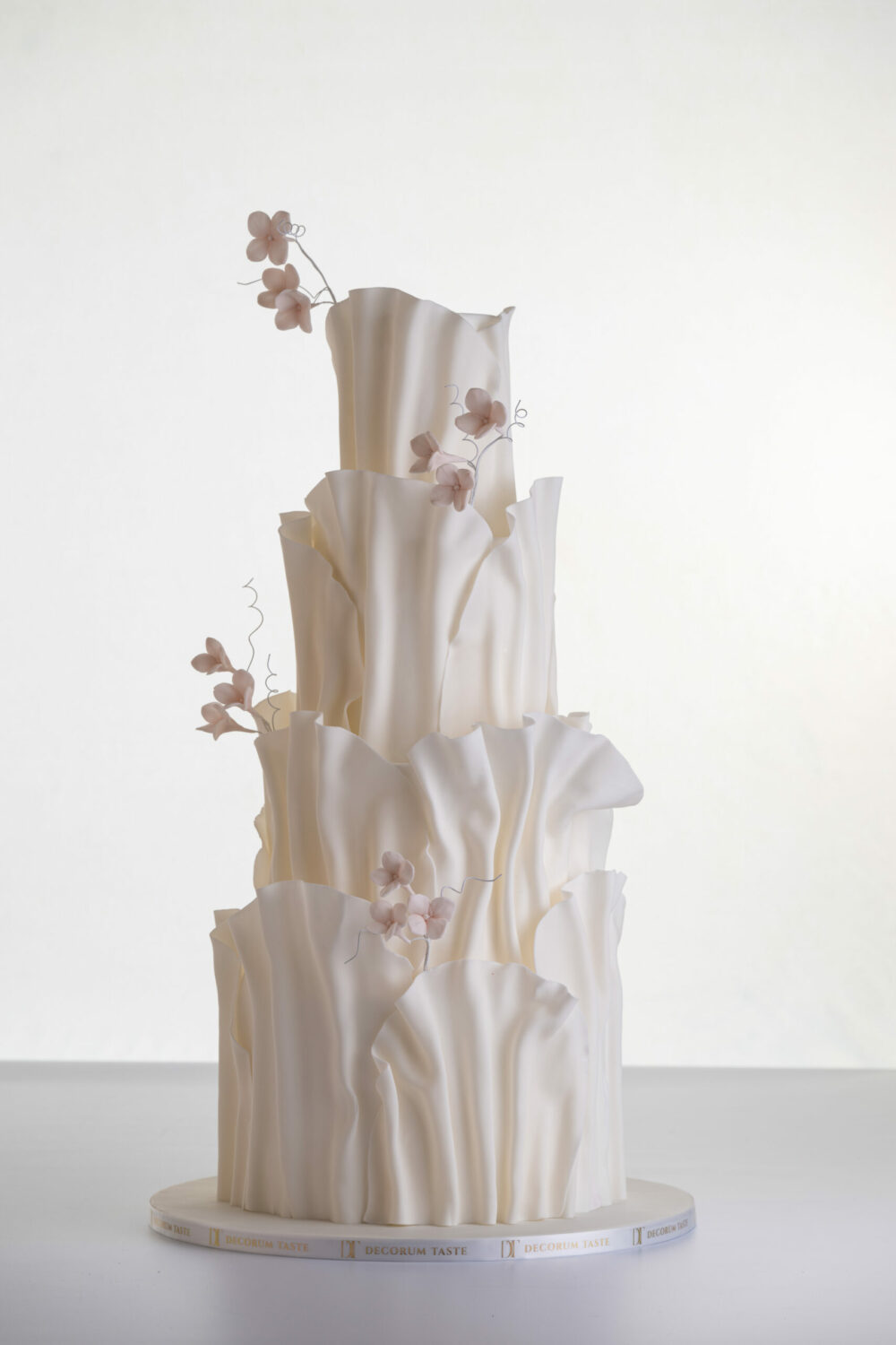 Four tier luxury contemporary, customisable, wedding cake, Modern Ruffles by Decorum Taste, with textured decorative folds and hand-crafted sugar flower stems.