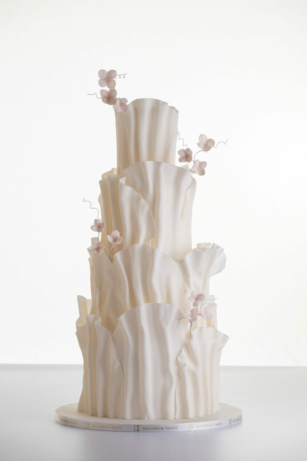 Four tier luxury contemporary, customisable, wedding cake, Modern Ruffles by Decorum Taste, with textured decorative folds and hand-crafted sugar flower stems.