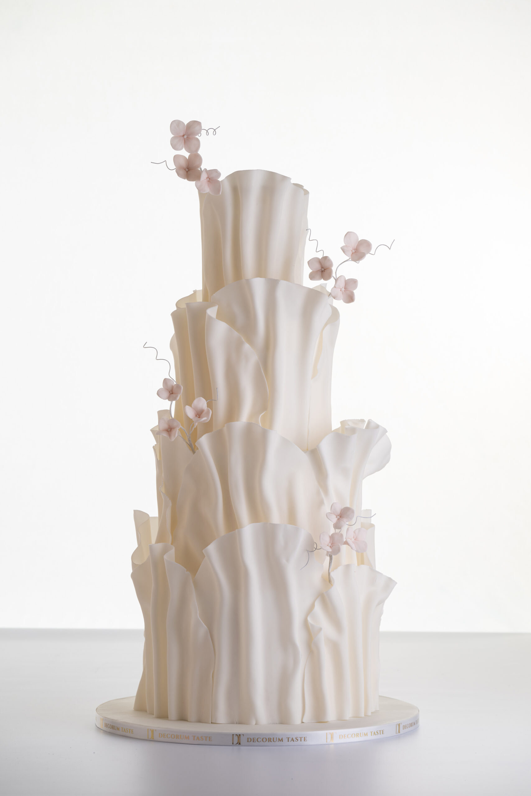 Four tier luxury contemporary, customisable, wedding cake, Modern Ruffles by Decorum Taste, with textured decorative folds and hand-crafted sugar flower stems.