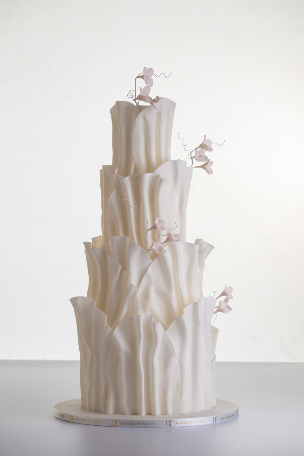 Four tier luxury contemporary, customisable, wedding cake, Modern Ruffles by Decorum Taste, with textured decorative folds and hand-crafted sugar flower stems.