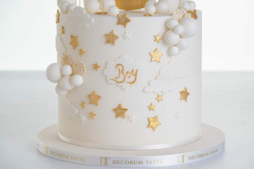 Detail of luxury contemporary, customisable, celebration cake, Moon Baby by Decorum Taste, in ivory with stars and clouds.