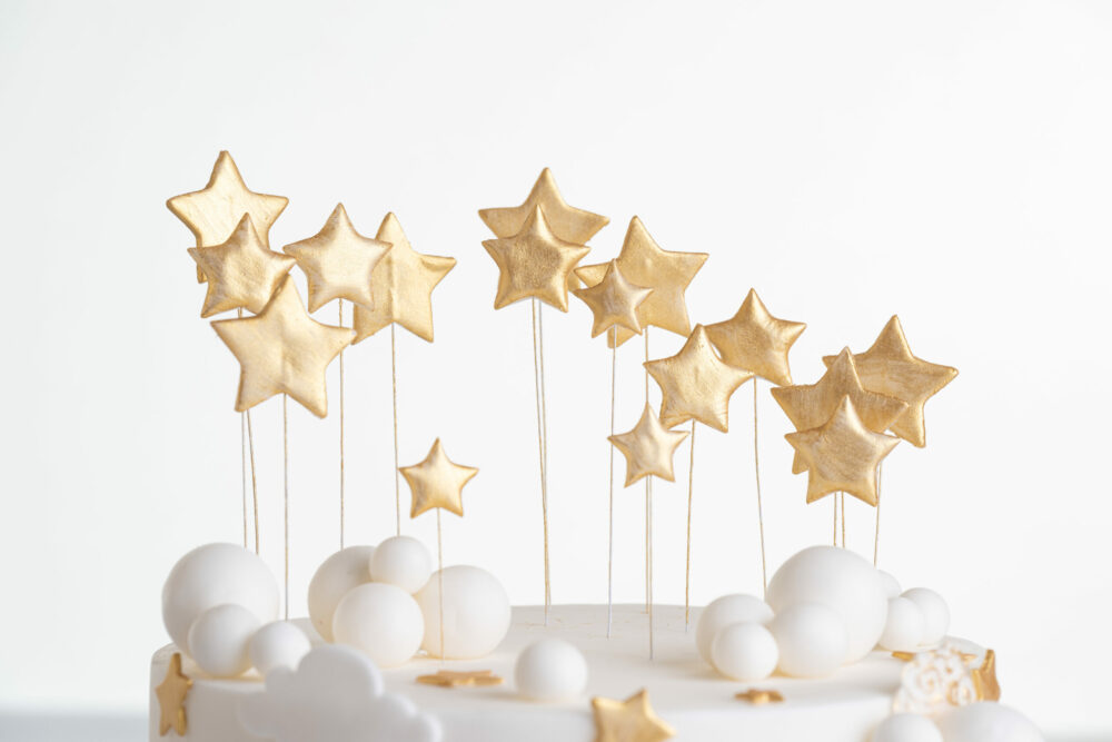 Top of luxury contemporary, customisable, celebration cake, Moon Baby by Decorum Taste, in ivory with stars and clouds.