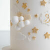 Detail of luxury contemporary, customisable, celebration cake, Moon Baby by Decorum Taste, in ivory with large golden moon, stars and clouds.