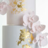 Detail of luxury contemporary, customisable, wedding cake, Orchid Heaven by Decorum Taste, with alternate tiers in blush pink and ivory, brushes of edible gold leaf and cascades of hand-crafted sugar orchids.