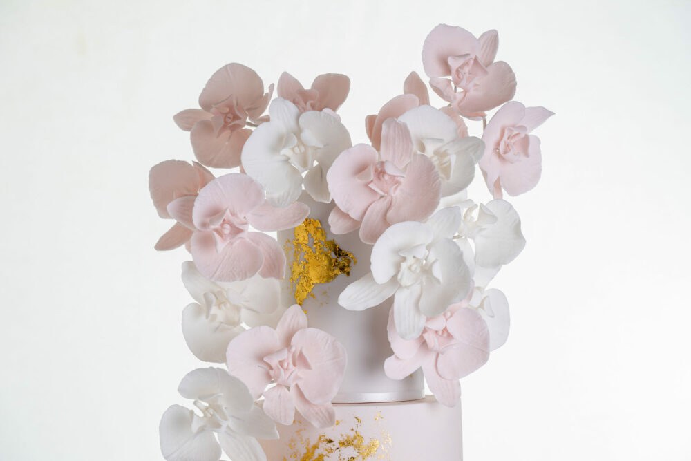 Top tier of luxury contemporary, customisable, wedding cake, Orchid Heaven by Decorum Taste, with brushes of edible gold leaf and bunches hand-crafted sugar orchids.