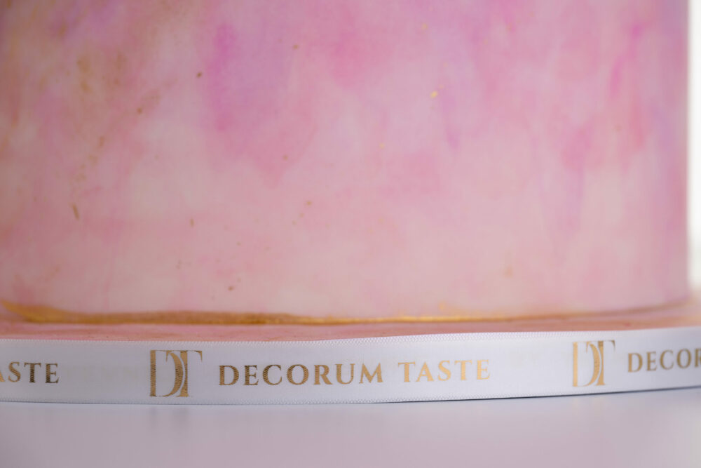 Bottom tier of luxury contemporary customisable wedding cake, Painted Blush by Decorum Taste, in hand-painted pink tones with a Decorum Taste branded ribbon.