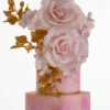 Top two tiers of luxury customisable contemporary wedding cake, Painted Blush, by Decorum Taste in pink hand-painted tones with a bouquet of large hand-crafted sugar roses, hydrangea petals and golden leaves.