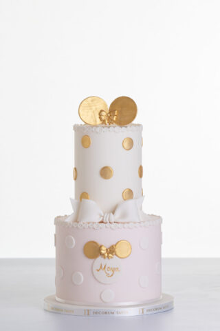 Two tier luxury contemporary, customisable, celebration cake, Polka Mouse by Decorum Taste, with decorative edible gold leaf circle embellishments, a pretty floral trim, cartoon mouse ears and sugar paste bow.