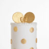 Top tier of luxury contemporary, customisable, celebration cake, Polka Mouse by Decorum Taste, with decorative edible gold leaf circle embellishments, a pretty floral trim and round mouse ears on top in gold with bow.