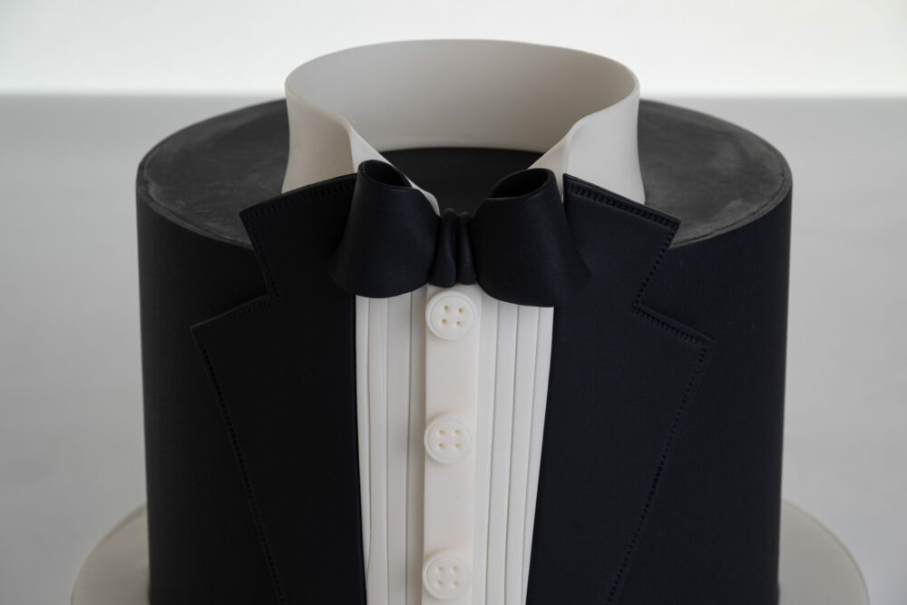 Top view of luxury contemporary, customisable, celebration cake, Tux Gent by Decorum Taste decorated in black the white of a formal shirt, tuxedo jacket and bow tie.