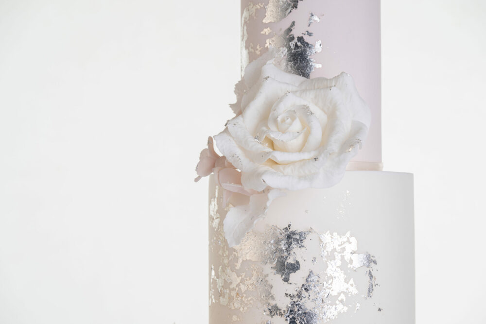 Top two tiers of luxury contemporary, customisable, wedding cake, Vintage Beauty by Decorum Taste with large hand-crafted sugar rose in ivory and brushed edible silver leaf.