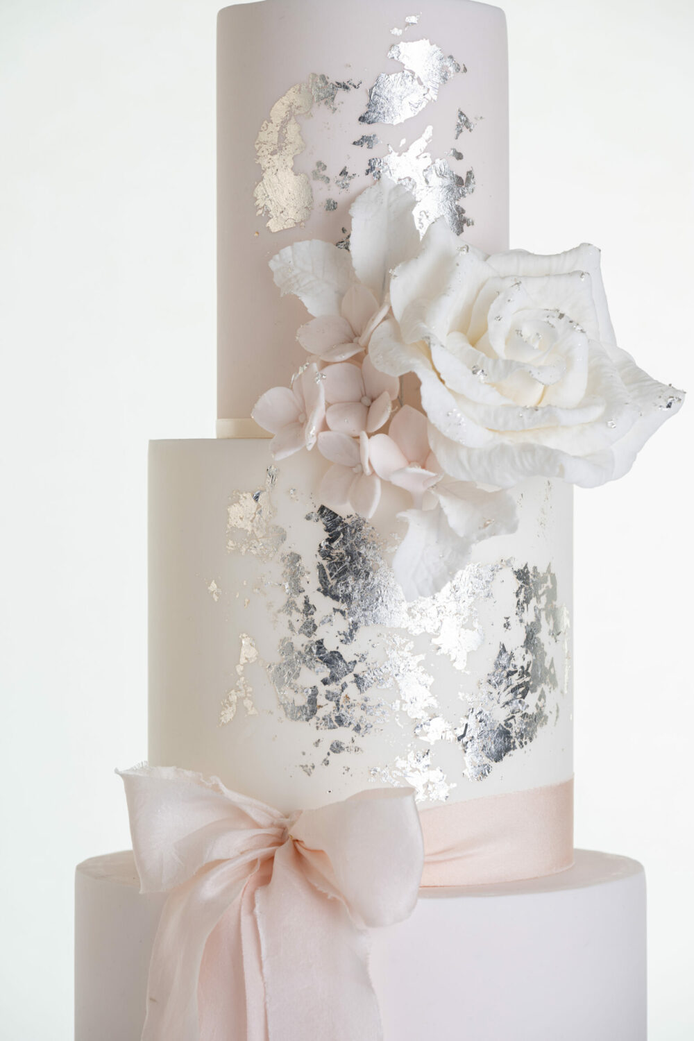 Top two tiers of luxury contemporary, customisable, wedding cake, Vintage Beauty by Decorum Taste with large hand-crafted sugar rose in ivory, brushed edible silver leaf and a silk bow.