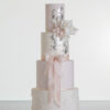 Four tier luxury contemporary, customisable, wedding cake, Vintage Beauty by Decorum Taste with large hand-crafted sugar rose in ivory, brushed edible silver leaf, decorative floral embellishments and a pink silk bow.