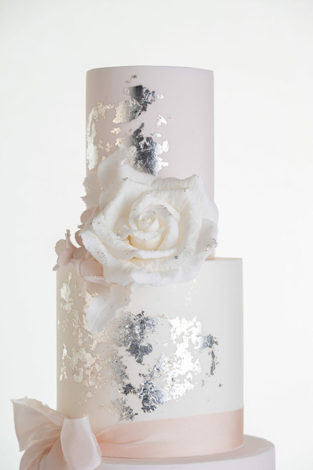 Top two tiers of luxury contemporary, customisable, wedding cake, Vintage Beauty by Decorum Taste with large hand-crafted sugar rose in ivory, brushed edible silver leaf and a silk bow.